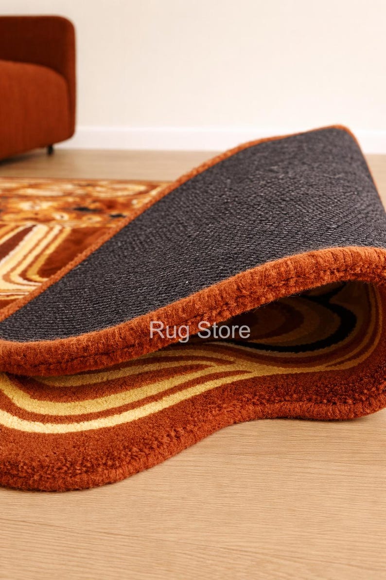 May include: A rolled-up area rug with a brown and yellow abstract pattern. The rug has a dark gray backing and a rust-colored border. The text "Rug Store" is visible on the edge of the rug.
