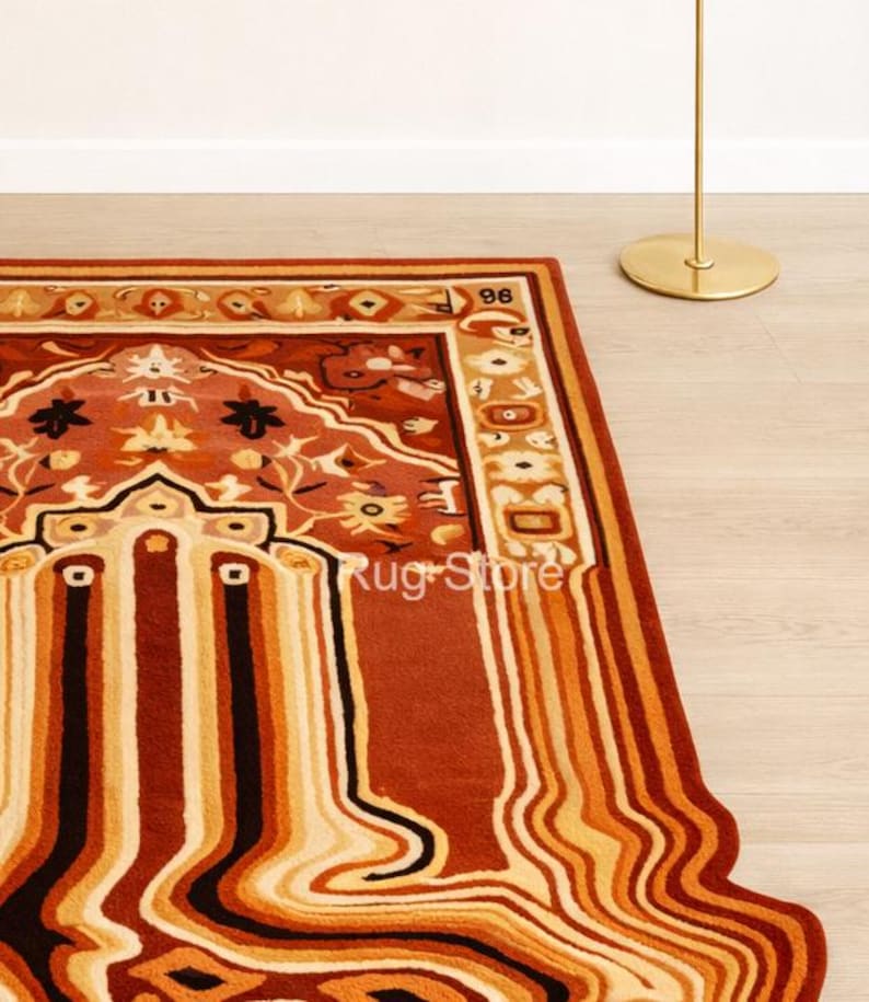 May include: A rectangular rug with a unique design featuring a mix of warm colors. The rug has a central pattern with floral and geometric elements in shades of red, orange, and beige. The border is a darker red, and the edge has a wavy, melted appearance.