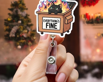 May include: A badge reel featuring a cartoon image of a black cat in a dumpster engulfed in flames. The dumpster has the words "EVERYTHING'S FINE" on it. The reel has a clear plastic strap and a metal clip.