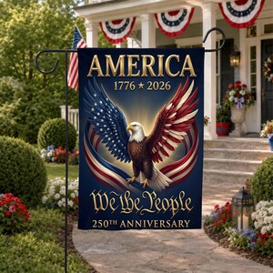May include: A rectangular garden flag with a dark blue background featuring a central bald eagle with wings spread. The text reads AMERICA 1776-2026 at the top and We the People 250TH ANNIVERSARY at the bottom in gold lettering with red and white accents.