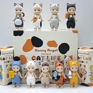 May include: A selection of Sonny Angel mini figures from the Cat Life series. The figures are dressed in cat-themed outfits, with various colours and accessories. The packaging features the series name and cat-themed graphics.