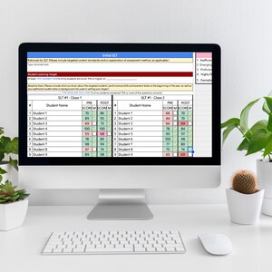 May include: A desktop computer displays a spreadsheet with student scores and performance data. The screen shows columns for student names, pre-test scores, and post-test scores. A keyboard, mouse, and small potted plants are in the foreground.