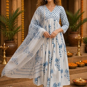 Pu&ograve; includere: Un completo in cotone bianco e blu con stampa floreale. L'outfit comprende un abito a maniche lunghe, pantaloni abbinati e una sciarpa trasparente. L'abito presenta uno scollo a V e una silhouette fluida. Adatto per occasioni casual o festive.