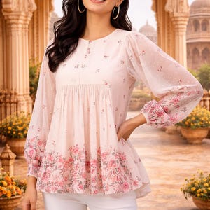 May include: A light pink blouse with a floral print and long, sheer sleeves. The blouse features a round neckline and a peplum hem. The sleeves and hem are adorned with a vibrant floral pattern. The model is wearing white pants.