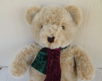 Peut inclure: Un ours en peluche beige portant une écharpe verte et bordeaux. L'ours a un nez brun et des yeux noirs.