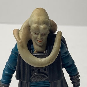 May include: A Star Wars action figure of a character with a pale green skin tone, wearing a black robe with a blue sash and a large, pale, fleshy neck ring. The figure has a menacing expression.