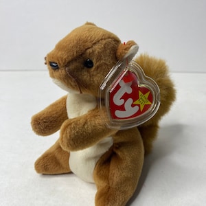 May include: A brown and white Ty Beanie Baby squirrel with a red heart-shaped tag that says "Ty Beanie Babies" and "Baby".