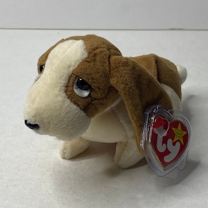 Può includere: Cane di peluche marrone e bianco Beanie Baby con un'etichetta a forma di cuore rosso che dice "Beanie Babies Baby".