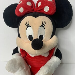 Pu&ograve; includere: Un giocattolo di peluche di Minnie Mouse con un vestito rosso con pois bianchi e un fiocco rosso con pois bianchi.
