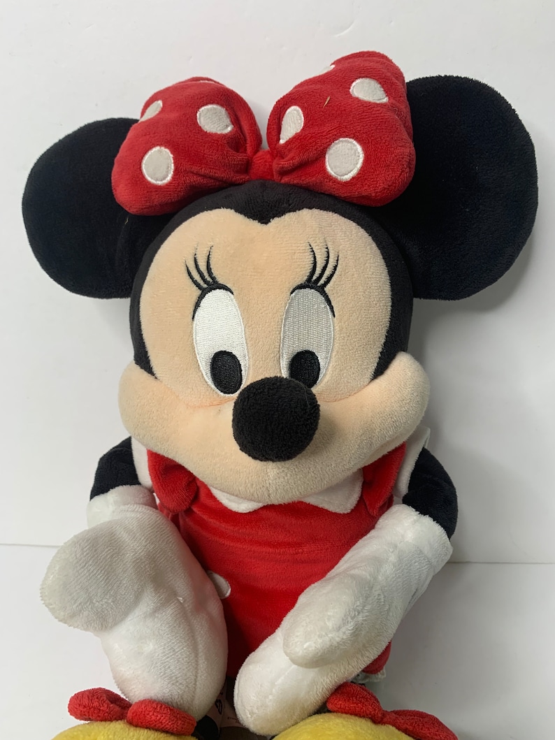 Pu&ograve; includere: Un giocattolo di peluche di Minnie Mouse con un vestito rosso con pois bianchi e un fiocco rosso con pois bianchi.