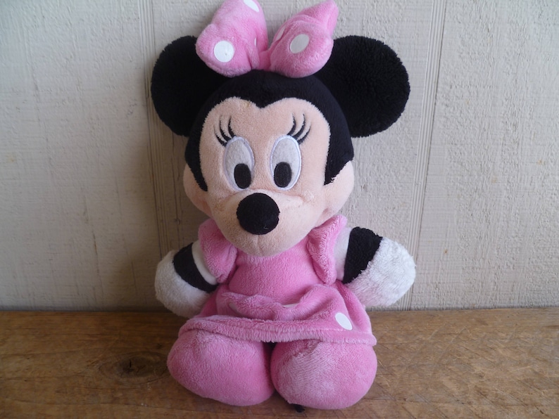 Puede incluir: Juguete de peluche rosa de Minnie Mouse con un vestido rosa con lunares blancos y un lazo rosa con lunares blancos.