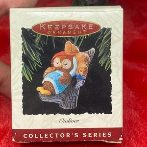 May include: A Keepsake Ornament box featuring a detailed illustration of two owls perched on a tree branch. The owls are brown and wearing blue and red clothing. The box reads "KEEPSAKE ORNAMENT" and "COLLECTOR'S SERIES".