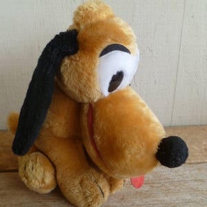 May include: A plush brown and black dog toy with floppy ears and a black nose. The dog has white eyes and a red tongue.