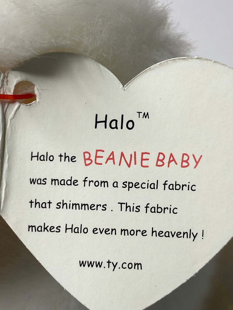 May include: White heart-shaped tag with the text "Halo&trade; Halo the BEANIE BABY was made from a special fabric that shimmers. This fabric makes Halo even more heavenly! www.ty.com"