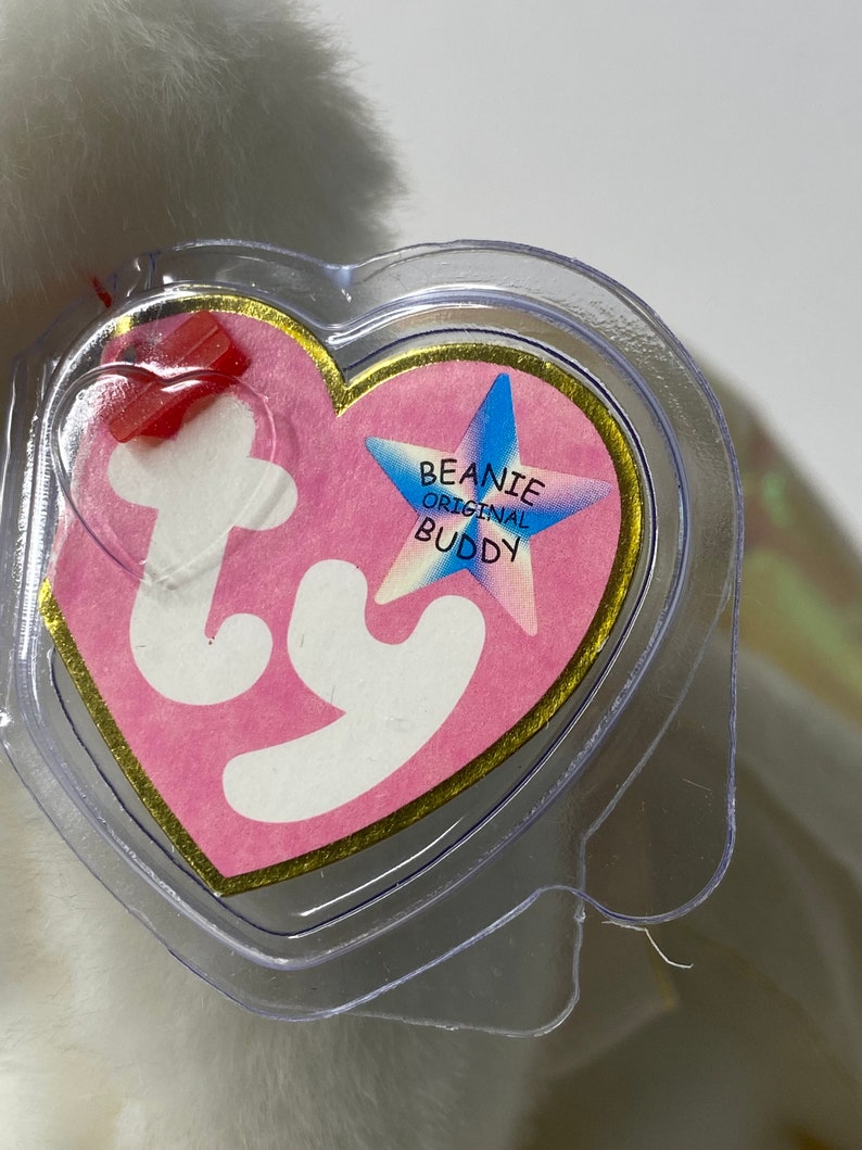 May include: White Beanie Baby with a pink heart-shaped tag that says "Beanie Original Buddy" with a blue star.