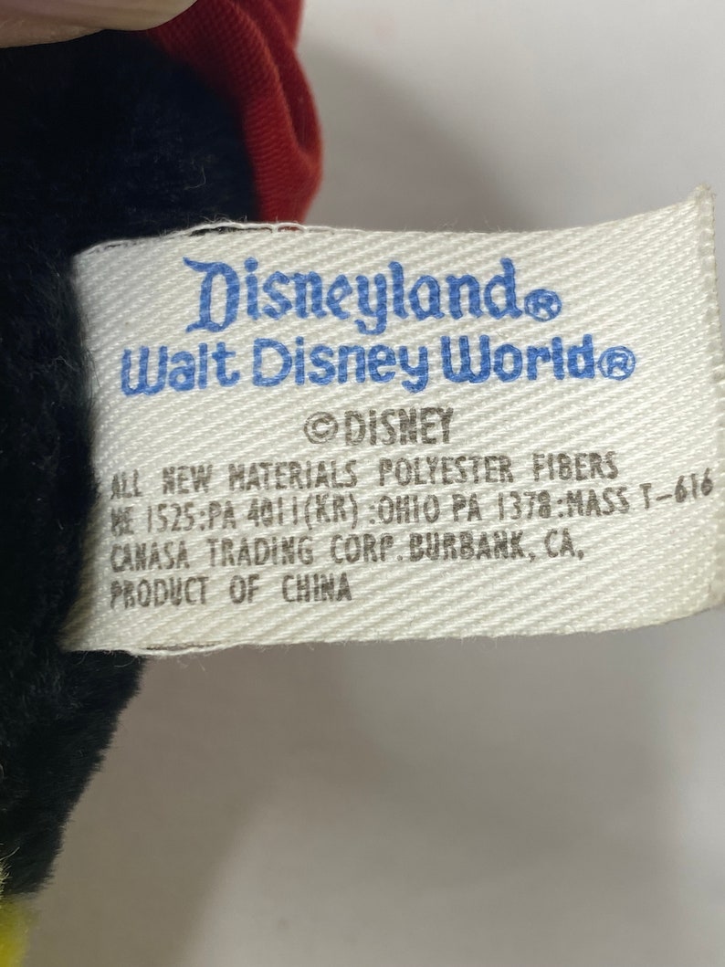 May include: White tag with blue text that reads "Disneyland Walt Disney World&reg; Disney" and "All new materials polyester fibers 1525:PA 4011(KR):Ohio PA 1378:MASS T-616 Canasa Trading Corp. Burbank, CA. Product of China."