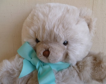 Peut inclure: Un ours en peluche blanc avec un nœud bleu clair autour du cou.