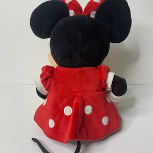 Pu&ograve; includere: Un giocattolo di peluche Minnie Mouse rosso con pois bianchi. Indossa un vestito rosso con pois bianchi e un fiocco nero con pois bianchi. Ha orecchie nere e una coda nera.