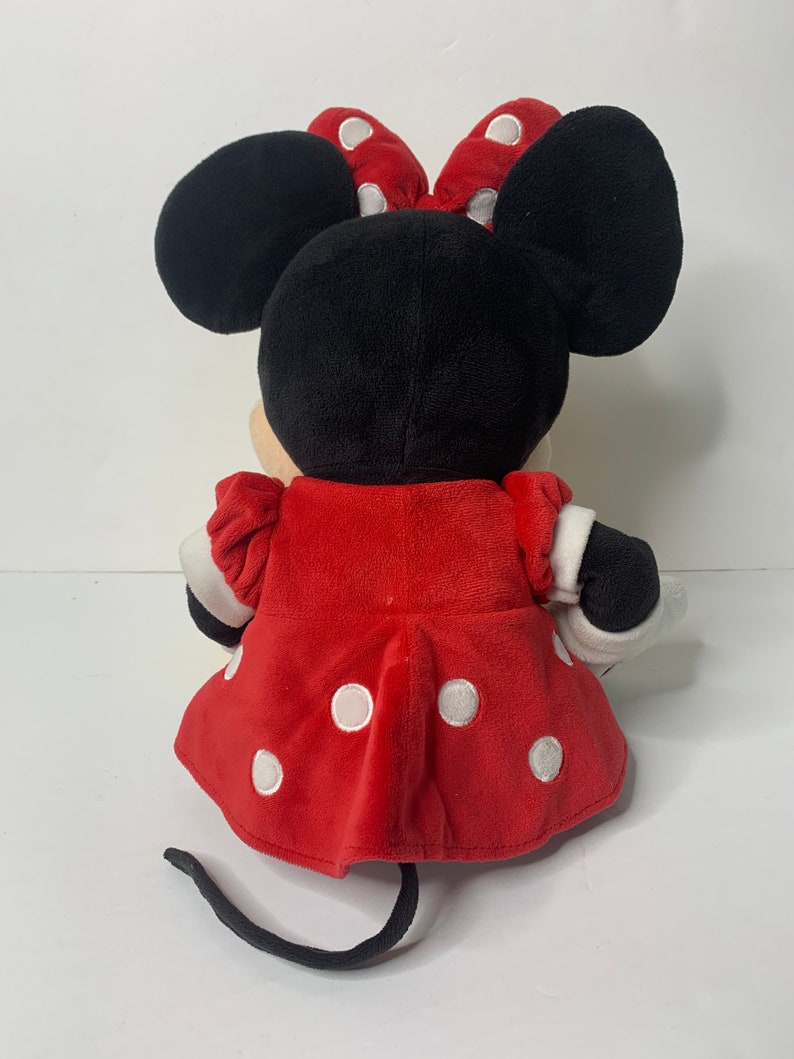 Pu&ograve; includere: Un giocattolo di peluche Minnie Mouse rosso con pois bianchi. Indossa un vestito rosso con pois bianchi e un fiocco nero con pois bianchi. Ha orecchie nere e una coda nera.