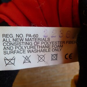 Może przedstawiać: Biała metka z czarnym tekstem, kt&oacute;ry brzmi "REG. NO. PA-60 ALL NEW MATERIALS CONSISTING OF POLYESTER FIBER AND POLYURETHANE FOAM SURFACE WASHABLE ONLY CE". Metka zawiera trzy symbole: pralkę z przekreślonym krzyżem, tr&oacute;jkąt z przekreślonym krzyżem i kwadrat z przekreślonym krzyżem.