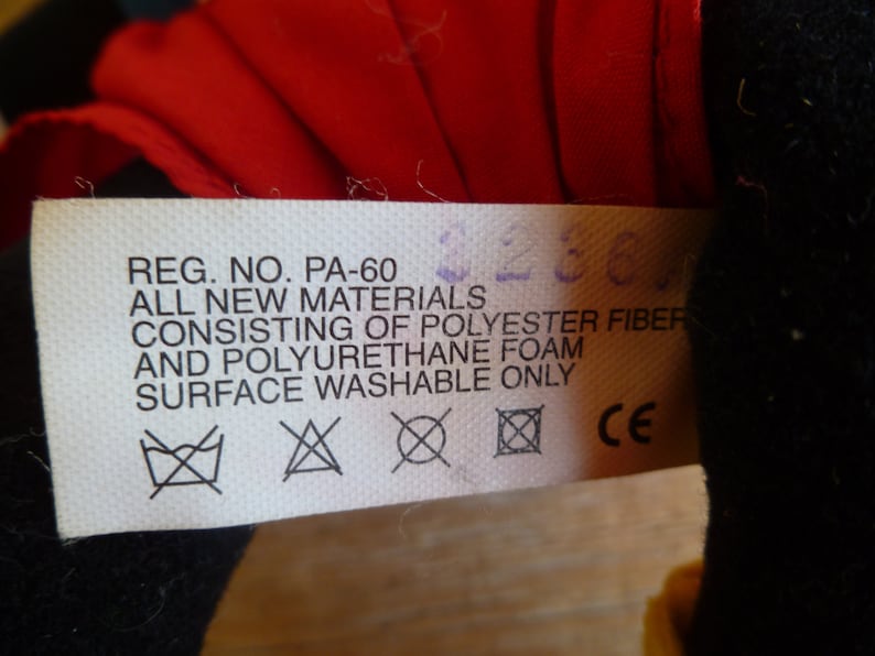 Może przedstawiać: Biała metka z czarnym tekstem, kt&oacute;ry brzmi "REG. NO. PA-60 ALL NEW MATERIALS CONSISTING OF POLYESTER FIBER AND POLYURETHANE FOAM SURFACE WASHABLE ONLY CE". Metka zawiera trzy symbole: pralkę z przekreślonym krzyżem, tr&oacute;jkąt z przekreślonym krzyżem i kwadrat z przekreślonym krzyżem.