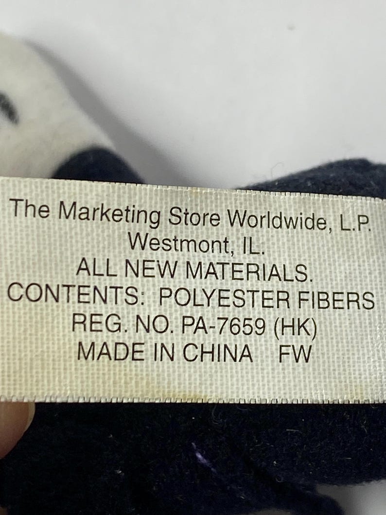 May include: White tag with black text on a black fabric background. The tag reads "The Marketing Store Worldwide, L.P. Westmont, IL. ALL NEW MATERIALS. CONTENTS: POLYESTER FIBERS REG. NO. PA-7659 (HK) MADE IN CHINA FW"