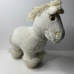 May include: White plush horse toy with brown eyes and a fluffy mane and tail.