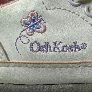May include: White leather children's shoe with purple embroidered butterfly and "OshKosh" text.