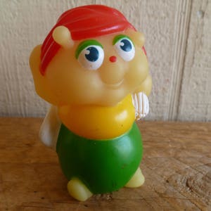 Könnte beinhalten: Ein gelbes und grünes Plastikspielzeug in Form einer Raupe mit rotem Kopf und großen blauen Augen.