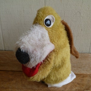 May include: A yellow and brown plush hand puppet with a white face and a black nose. The puppet has one large, black eye with a white circle around it.