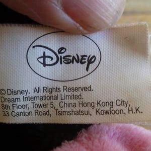 Puede incluir: Etiqueta blanca con texto negro que dice "Disney" en un c&iacute;rculo y "Disney. Todos los derechos reservados. Dream International Limited. 8&ordm; piso, Torre 5, China Hong Kong City, 33 Canton Road, Tsimshatsui, Kowloon, H.K."