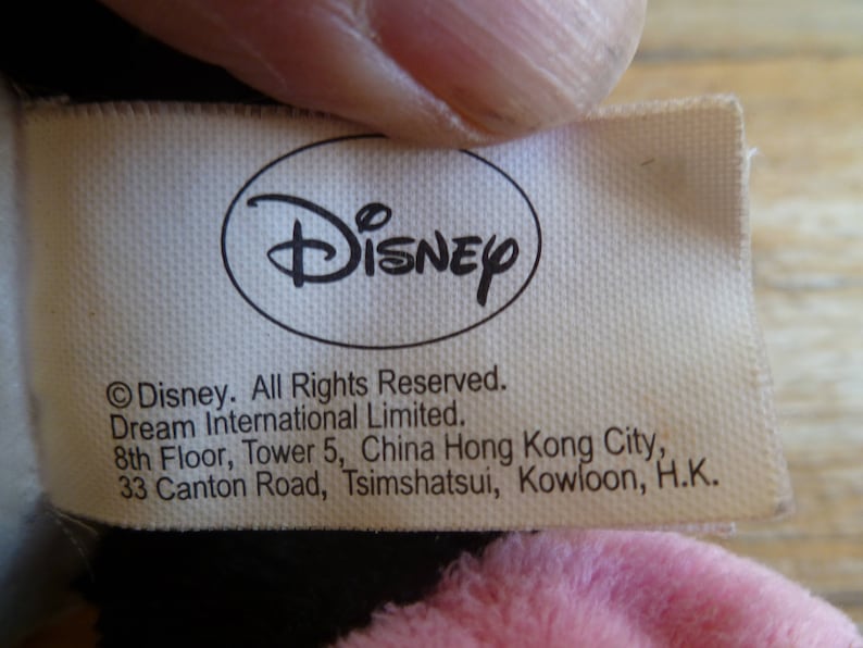 Puede incluir: Etiqueta blanca con texto negro que dice "Disney" en un c&iacute;rculo y "Disney. Todos los derechos reservados. Dream International Limited. 8&ordm; piso, Torre 5, China Hong Kong City, 33 Canton Road, Tsimshatsui, Kowloon, H.K."
