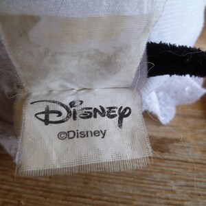 May include: White fabric tag with black text that reads "Disney" and "&copy;Disney".