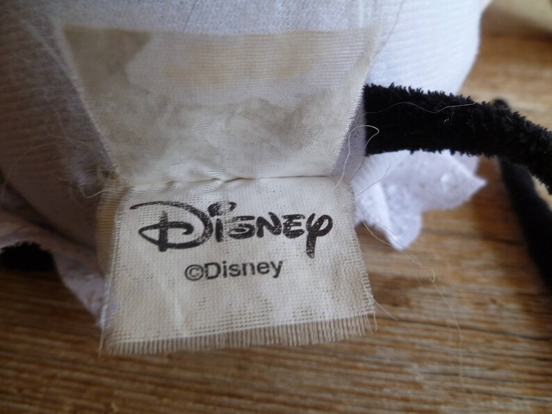 May include: White fabric tag with black text that reads "Disney" and "&copy;Disney".
