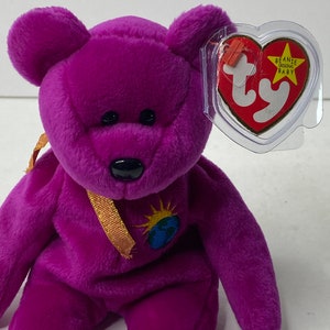 Puede incluir: Peluche morado Beanie Baby con una cinta dorada y una etiqueta que dice "Beanie Original Baby".