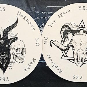 May include: Two circular divination boards with black and white illustrations. One features a goat head with skulls, the other a ram skull within a triangle. Text includes "Yes", "No", "Maybe", and "Try again".