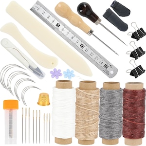 Op de afbeelding: Een lederbewerking set met diverse gereedschappen, waaronder naalden, garenspoelen, een liniaal (15 cm), priem en bindclips. De set bevat ook een vingerhoed, een snijgereedschap en decoratieve bloemspelden. De draadkleuren zijn wit, beige, grijs en bordeaux.