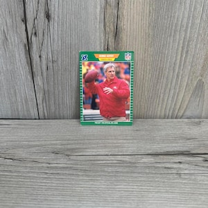 May include: A green and white football card featuring George Seifert, coach and trainer. The card shows a photo of Seifert in a red jacket throwing a football. The card has the NFL logo and the text "PRO SET - THE OFFICIAL NFL CARD."