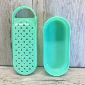 Peut inclure: Un ensemble de cuisine vert menthe composé d'une râpe perforée avec une poignée et d'un récipient ovale assorti. Les deux pièces sont en plastique et sont conçues pour la préparation des aliments.