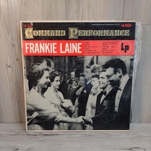 Puede incluir: Álbum de vinilo LP vintage "Command Performance" de Frankie Laine. La portada del álbum presenta una foto en blanco y negro de un grupo de personas. El título del álbum y el nombre del artista están en texto rojo y blanco.