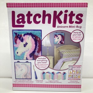 Peut inclure: Kit LatchKits Unicorn Mini-Rug. La boîte montre un mini-tapis licorne fini avec un design bleu, rose et violet. Le kit comprend une toile codée par couleur de 30 cm x 28 cm, un outil de crochet et des paquets de fil.