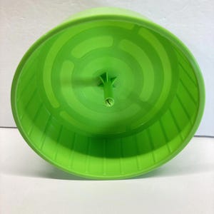 May include: A bright green plastic hamster wheel. The wheel has a cylindrical shape with a ridged running surface and a central support structure. The wheel is designed for small pets to exercise.