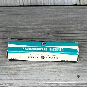 May include: A vintage General Electric semiconductor rectifier box. The box is white with a teal stripe and text that reads "SEMICONDUCTOR RECTIFIER." The GE logo is visible. Made in the USA.
