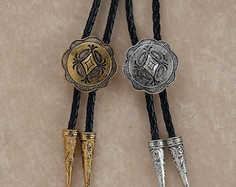 May include: Two bolo ties with black braided cords. One has a gold-toned, floral-patterned medallion and matching tips. The other has a silver-toned medallion and tips. The bolo ties are a Western-style accessory.