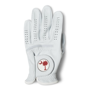 May include: White golf glove with a palm tree and crescent moon emblem. The glove has small ventilation holes and a textured grip area. The emblem is red and white, and the glove is made of a smooth, durable material.