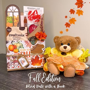 May include: A brown paper gift package decorated with autumn leaf stickers, a pumpkin illustration, and a tag labeled Fall Romance. It contains a Craftmix Espresso Martini packet, a red candle, and a reading list. Beside it sits a brown plush teddy bear wearing a yellow and orange checkered dress.