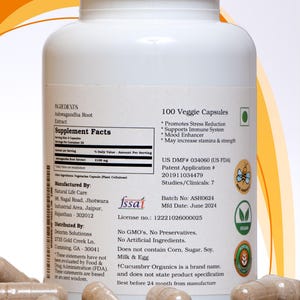 May include: A white bottle of 100 veggie capsules, containing Ashwagandha Root Extract. The label includes supplement facts, manufacturing details, and a vegan certification. Capsules are visible in the foreground.