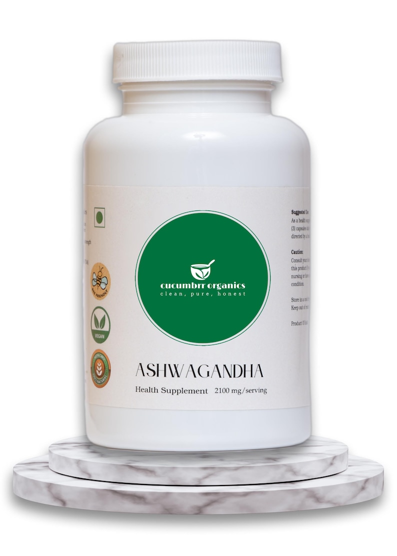 May include: A white bottle of Ashwagandha health supplement. The bottle has a green circular label with the text "cucumber organics clean, pure, honest". The label also includes the text "ASHWAGANDHA Health Supplement 2100 mg/serving". The bottle is on a marble stand.