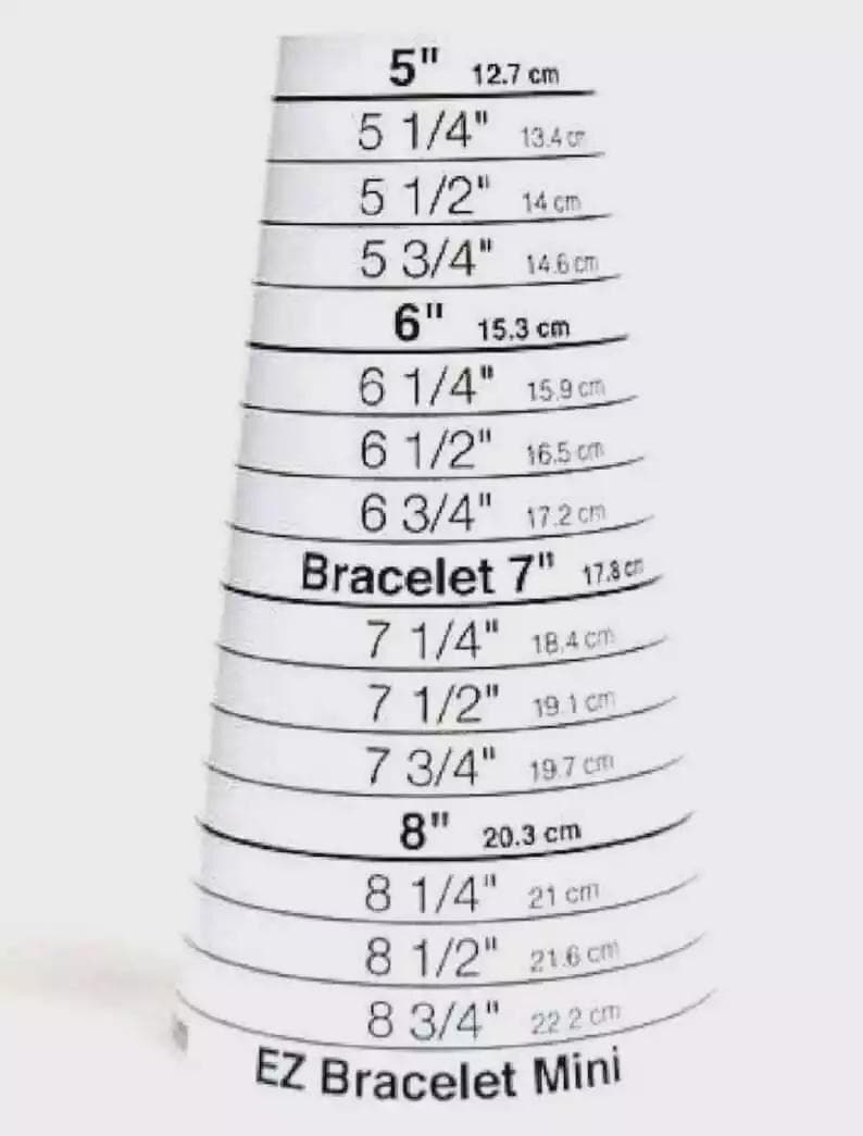 Może przedstawiać: Biały miernik EZ Bracelet Mini z czarnym tekstem wskazującym rozmiary bransoletki od 5 cali (12,7 cm) do 8 3/4 cala (22,2 cm). Każdy rozmiar jest oznaczony odpowiednikiem w calach i centymetrach.