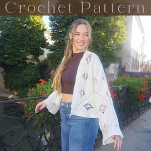 Könnte beinhalten: Eine Frau trägt eine weiße Häkeljacke mit floralem Muster, kombiniert mit einem braunen Oberteil und blauen Jeans. Der Text "Crochet Pattern" ist im Bild zu sehen. Im Hintergrund sind eine Brücke, Wasser und Bäume.